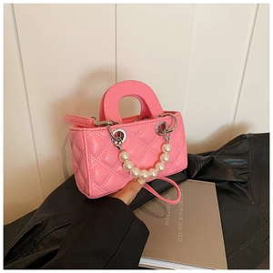 Detailed shot of pink quilted mini bag with pearl handle and silver hardware