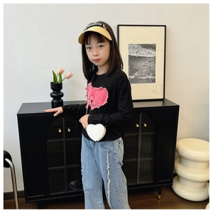 Vue détaillée d'une tenue de fille avec t-shirt noir à patch cœur et sac à bandoulière blanc