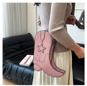 Close-up of pink boot-shaped crossbody bag with star patches and metal chain strap