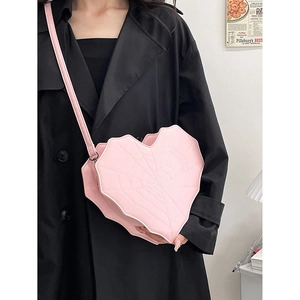 Sac à bandoulière rose en forme de cœur avec coutures toile d'araignée porté par modèle