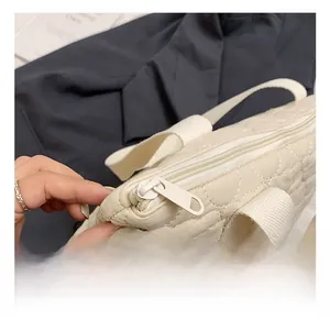 Detail of cream quilted handbag showing metal zipper and heart pattern texture