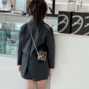 Mini-Eimerbeutel mit Leopardenmuster und Goldkette über schwarzem Lederblazer