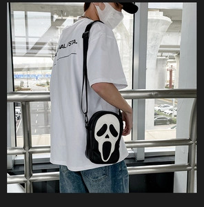 Detailed view of the Ghostface mask shaped crossbody bag on a street style model