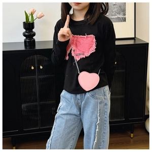 Sac à bandoulière rose en forme de cœur avec t-shirt noir à nœud et jean en denim