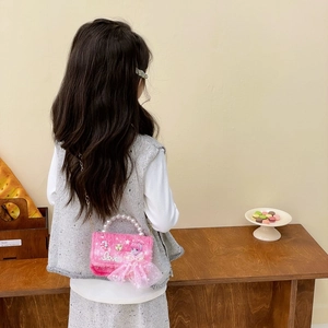 Rosa Plüsch-Kinderhandtasche mit Perlengriff und Kette getragen von einem Kind zu Hause