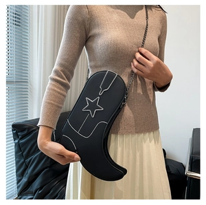 Detail view of black boot-shaped crossbody bag featuring white star and silver chain