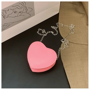 Détail du mini sac à bandoulière rose en forme de cœur avec une chaîne argentée