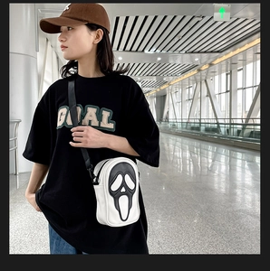 Close-up of small white leather crossbody bag with iconic black Ghostface scream design