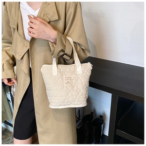 Close-up of beige quilted tote bag with wavy stitching and all about baby label