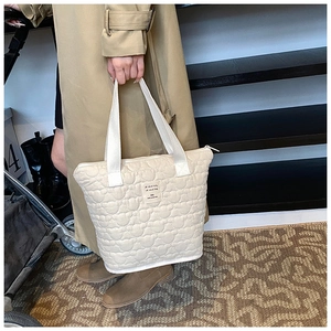 Close-up of beige quilted tote bag with heart pattern and lovely things store label