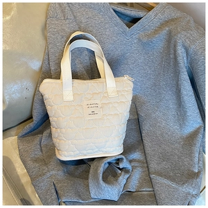 Detail of cream quilted tote bag featuring soft bear pattern stitching and zip closure