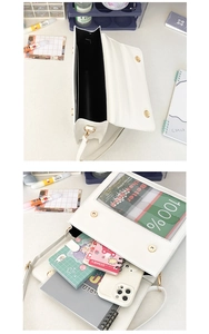 Detailed view of white crossbody bag showing interior capacity with notebooks and phone