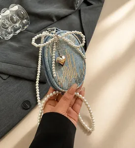 Detail of mini denim coin purse with sequins, pearl handle, and heart metal pendant