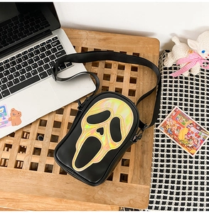 Top view of a black crossbody bag with laser holographic Scream mask print and strap