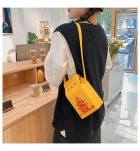 Close-up of a creative yellow takeout box shaped crossbody bag with a chain strap