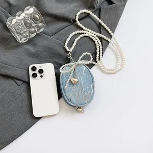 Detail of blue denim mini bag with silver sequins, pearl strap and heart charm