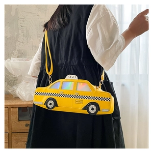 Detail view of yellow taxi-shaped crossbody bag featuring NYC TAXI text and checkered stripes