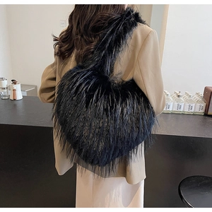 Détail d'un sac à bandoulière en peluche noire en forme de cœur porté par un modèle