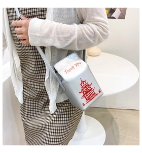 Close-up of a silver Chinese takeout box style crossbody bag with red tower print and chain