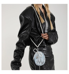 Mini sac denim bleu à paillettes, nœud en perles et cœur argenté sur veste en cuir