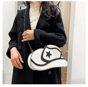 Detail view of white baseball cap shaped crossbody bag with black star and silver chain