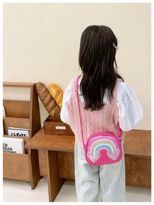 Detailed back view of a child wearing a rose pink rainbow heart crossbody bag
