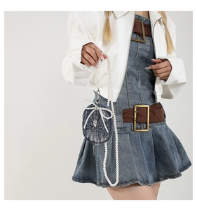 Détail d'un mini sac en jean bleu avec nœud en perles et bandoulière en chaîne de perles