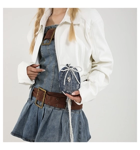 Détail d'un mini sac en denim bleu avec nœud en perles blanches et pendentif cœur