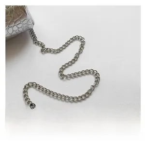 Detail view of silver crocodile pattern texture and metallic chain strap on mini bag