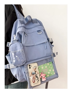 Detail view of light blue nylon backpack featuring multi-pocket design and transparent front pocket