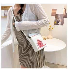 Detailed view of white takeout box style crossbody bag with red tower print on model