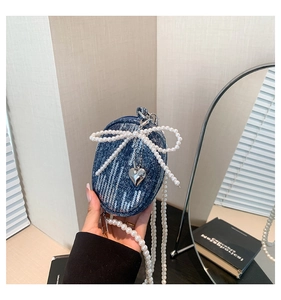 Détail du mini sac en denim avec paillettes, nœud en perles et pendentif cœur