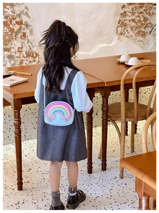 Close-up of blue sequin crossbody bag with rainbow heart design on child model