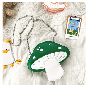 Detail of the green mushroom-shaped crossbody bag with white dots and silver metal chain strap