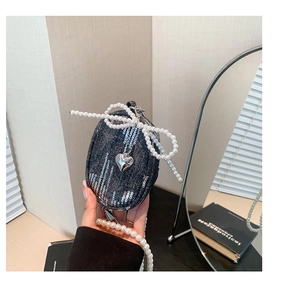 Détail du mini sac en denim avec paillettes argentées, chaîne en perles et breloque en cœur