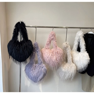 Détail de cinq sacs en fausse fourrure en forme de cœur, coloris noir, violet, rose et blanc