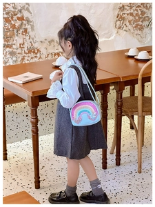 Cute light blue kids crossbody bag with sequin rainbow and heart on a young girl model