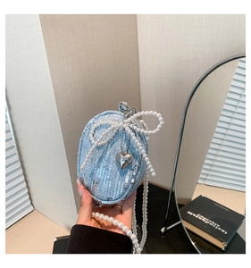 Détail du mini sac en jean bleu avec paillettes, nœud en perles et pendentif cœur