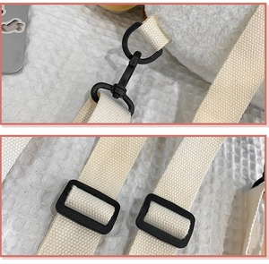 Detail of adjustable cream canvas strap with durable black plastic buckle on plush bag