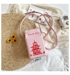 Pink milk box crossbody bag with tower print and flowers in a cozy lifestyle setting