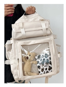 Detail view of cream canvas backpack featuring a transparent PVC window and side buckle straps