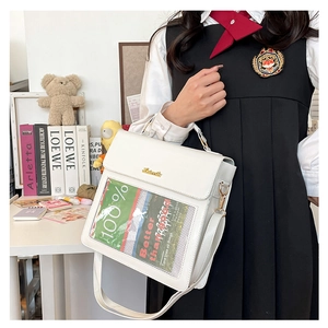 Detail showing the white leather school bag with a clear PVC slot and adjustable strap