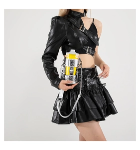Detail of a bright yellow mini crossbody bag with metallic frame on a black leather outfit