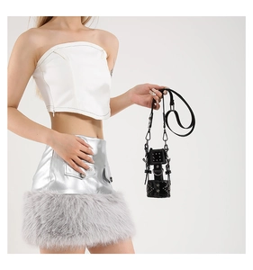 Detail of a black punk style mini bag with silver rivets and D-rings on a fashion model