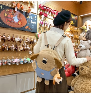 Detail view of a cute plush dog backpack with blue overalls and adjustable straps