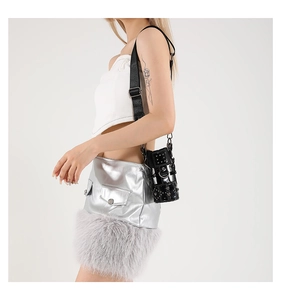 Detail of a black punk-style crossbody bag with silver studs and metal frame on a model
