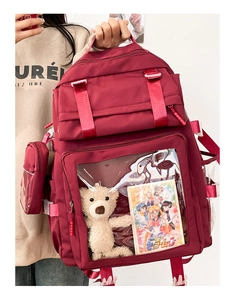 Detail of burgundy school backpack featuring clear window pocket and plush bear charm