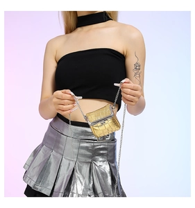 Mini gold crocodile pattern chain bag worn by model over a silver pleated skirt