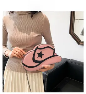 Detail of pink cowboy hat-shaped crossbody bag with black star and silver chain strap
