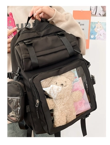 Detailed view of black nylon ita bag featuring a large clear window with a plush bear toy